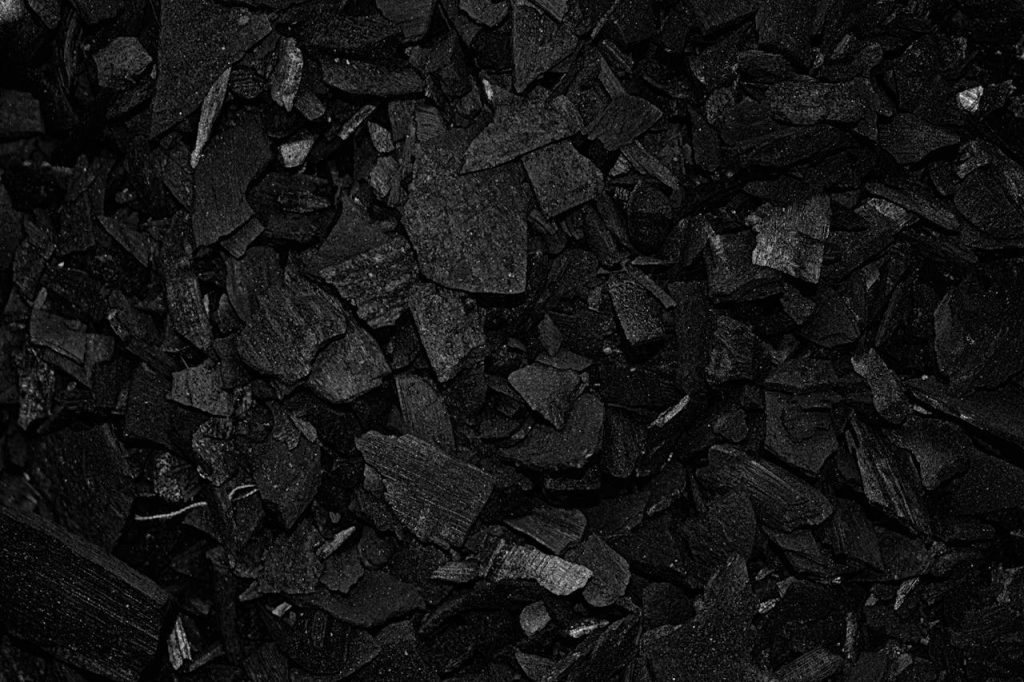 Detailed view of black charcoal pieces arranged in a pile for grilling or art use.